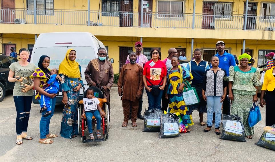 Persons with Disabilities standing together with food package collected from the Lagos State Government