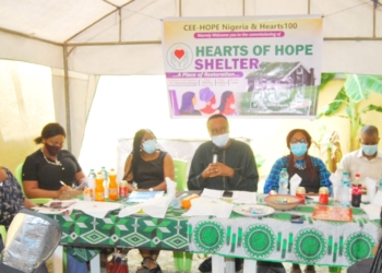 3 women, two men sitting on a high table facing the audience. One of them holding a microphone to speak