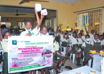 School girls raising sanitary pads in their hands and some are holding a banner in the front
