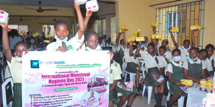 School girls raising sanitary pads in their hands and some are holding a banner in the front