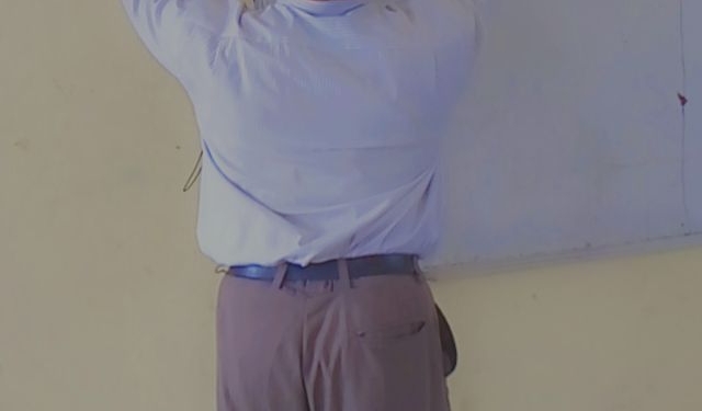 Man standing, writing on a board with his marker.