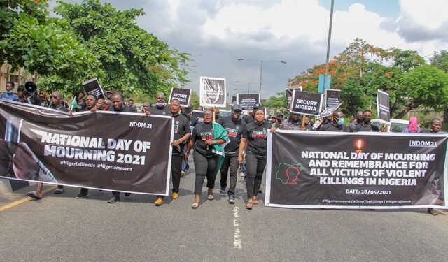 Protesters walking on the road holding placards and banner, complaining about insecurity in Nigeria