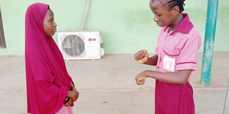 Two female deaf students standing together and communicating in sign language