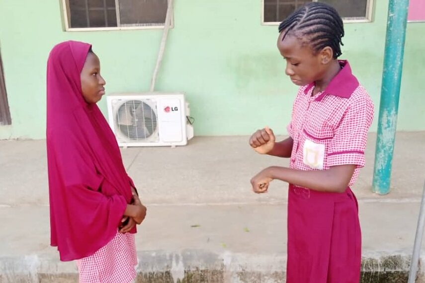 Two female deaf students standing together and communicating in sign language