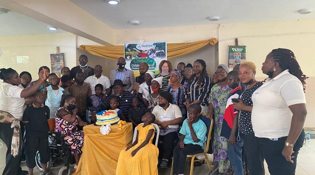 group photograph, some seated while some stood. There is a cake on a table in front of them