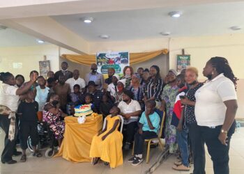 group photograph, some seated while some stood. There is a cake on a table in front of them