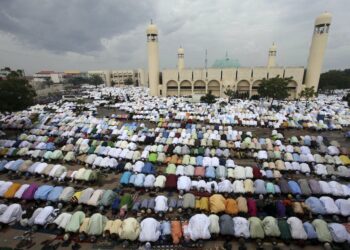 Group of muslims observing prayer in an open field