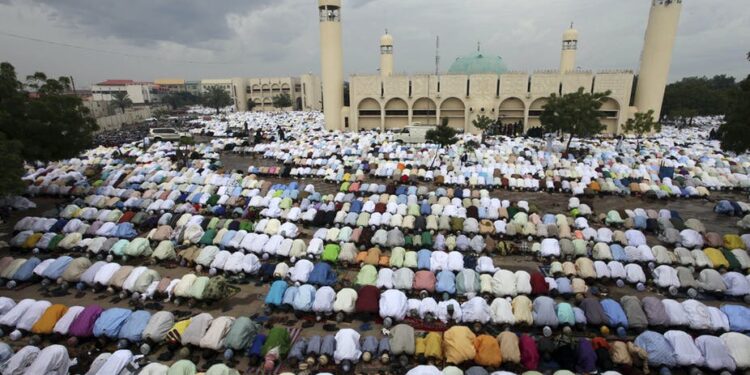 Group of muslims observing prayer in an open field