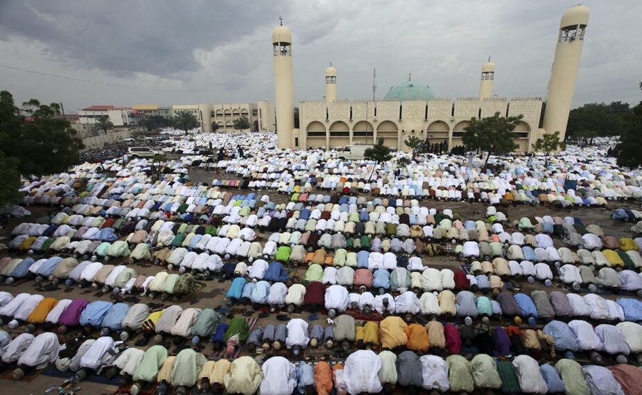 Group of muslims observing prayer in an open field