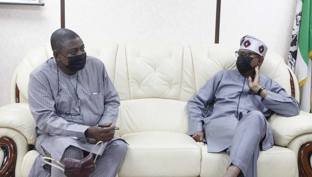 Two men seated on a couch and looking at each other