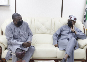 Two men seated on a couch and looking at each other