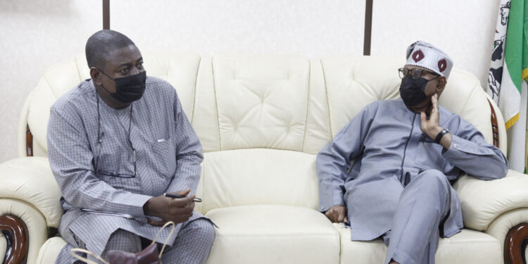 Two men seated on a couch and looking at each other