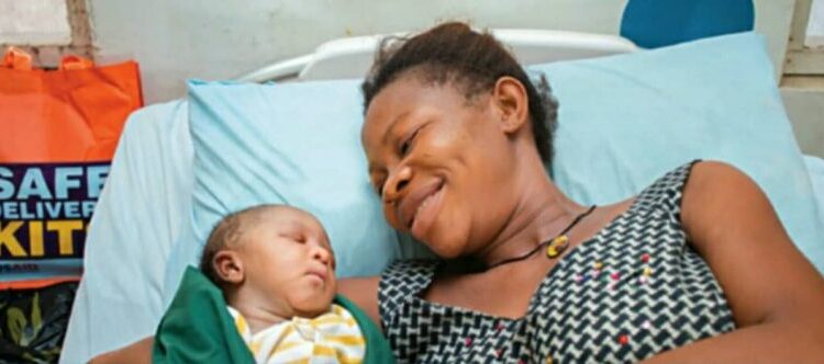 A woman on a bed with her baby, smiling at her baby