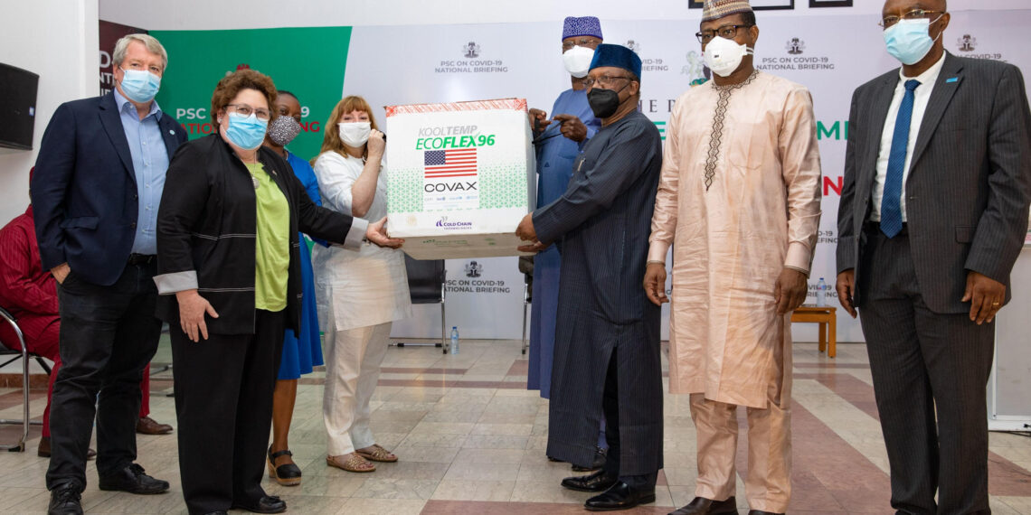 Group picture with boxes of vaccine in the centre