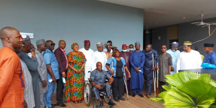 Image of a group of persons standing outdoor. One of them is on a wheel chair