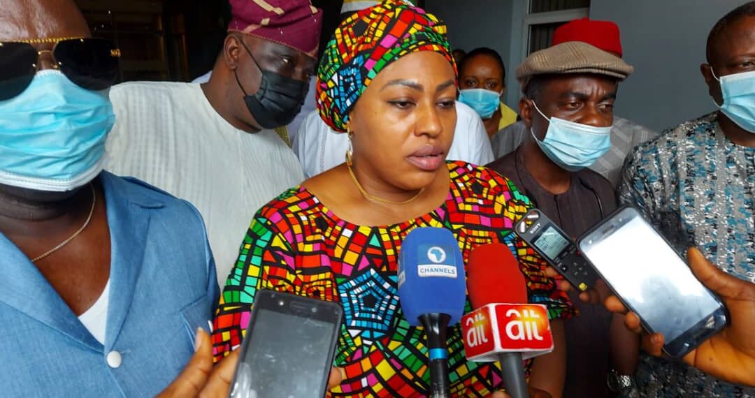 Chairman, House Committee on Disability at the Federal House of Representatives, Honourable Marian Onuoha (backed by few few honourable members) is standing with microphones and recorders pointed at her outdoor