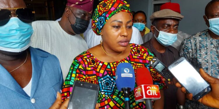 Chairman, House Committee on Disability at the Federal House of Representatives, Honourable Marian Onuoha (backed by few few honourable members) is standing with microphones and recorders pointed at her outdoor