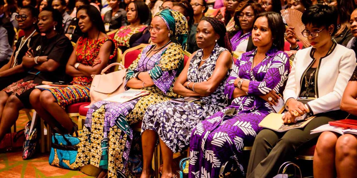 A group of women indoor sitting down keening paying attention