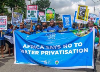 Group of people holding placards and banner to advocate for an end to water privatization
