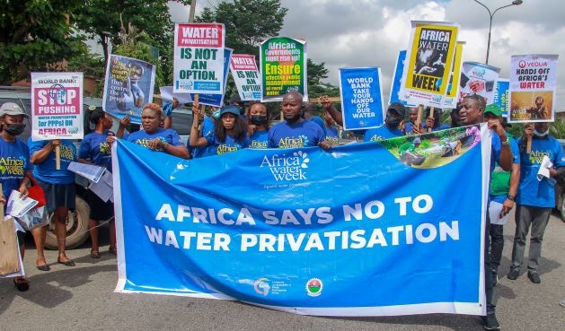 Group of people holding placards and banner to advocate for an end to water privatization