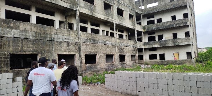 An uncompleted building with blocks on the floor and some people are walking towards the building