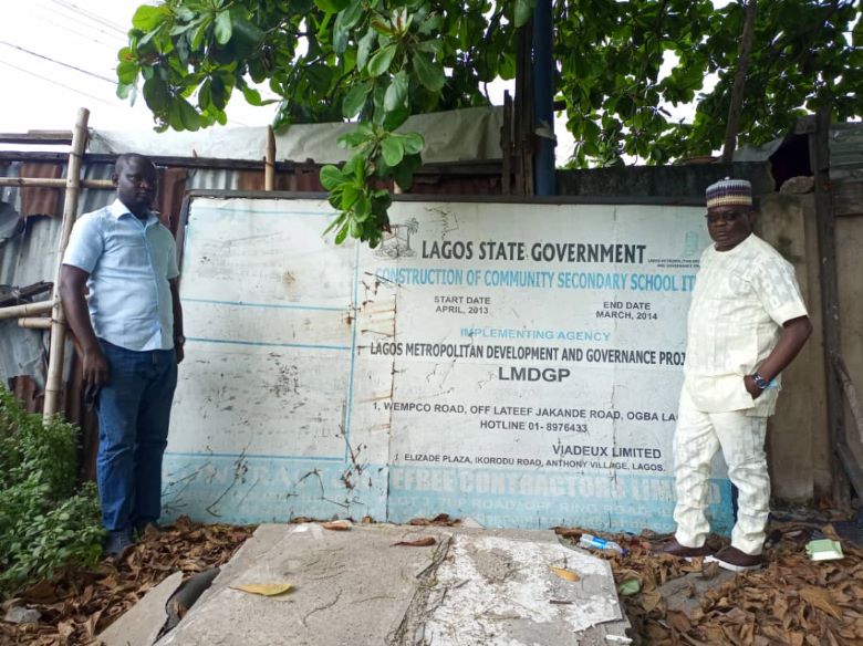 Two people standing beside a sign post which captures the details of the project