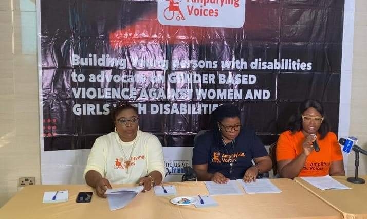 three people seated and one of them holding a microphone