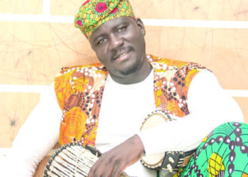 Man in a sitting positing with talking drums