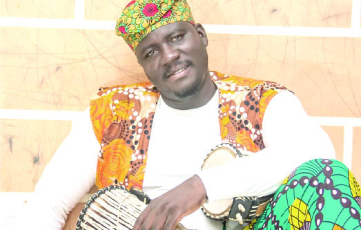 Man in a sitting positing with talking drums