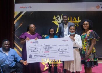 People in a group picture and they're all holding a big cheque and there is someone on a wheel chair