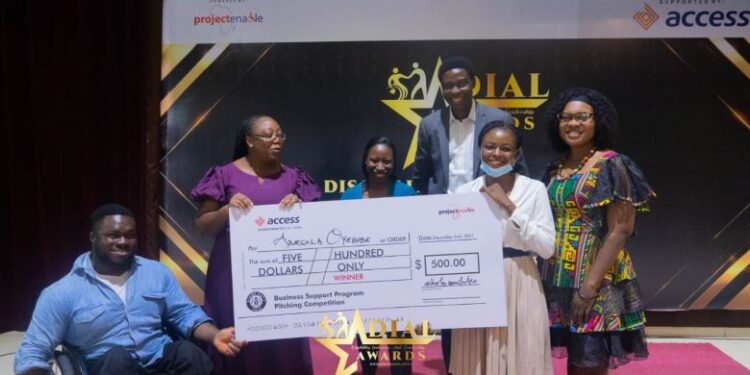 People in a group picture and they're all holding a big cheque and there is someone on a wheel chair