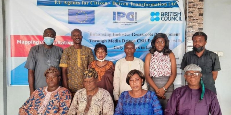 People in a group picture, some are seated while some are standing. There is a banner in the background