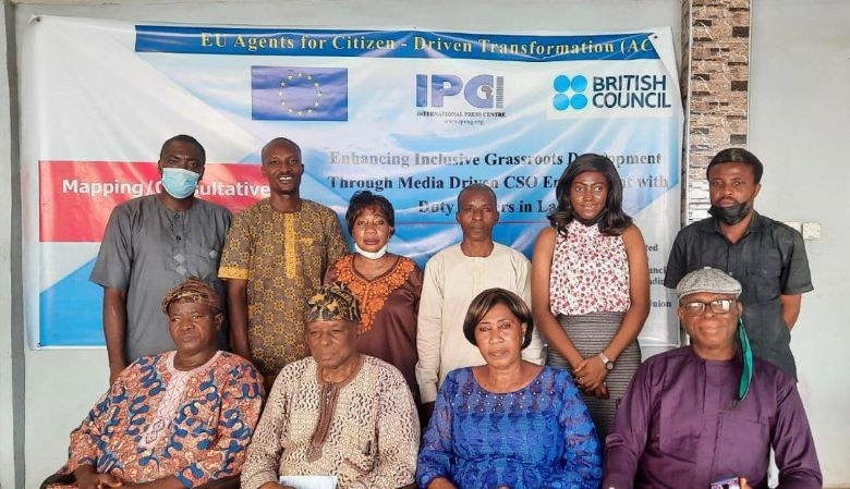 People in a group picture, some are seated while some are standing. There is a banner in the background