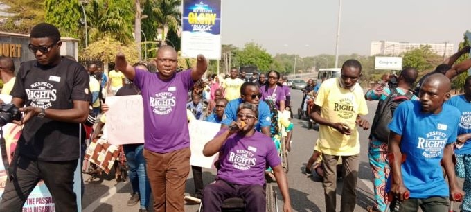 People on the road doing an advocacy walk, most of them are PWDs and are carrying placards