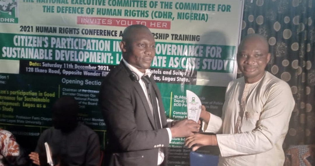 Mr David O. Anyaele receiving an award from Dr Kahinde Taiga. Both are indoors standing