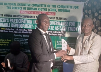 Mr David O. Anyaele receiving an award from Dr Kahinde Taiga. Both are indoors standing