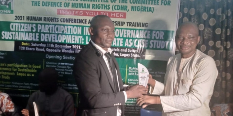 Mr David O. Anyaele receiving an award from Dr Kahinde Taiga. Both are indoors standing