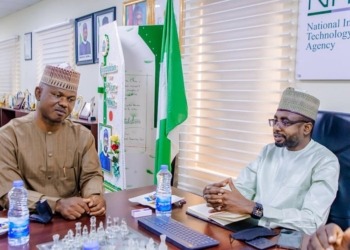 The Director-General, National Information Technology Development Agency (NITDA), Kashifu Inuwa and the Executive Secretary, National Commission for People with Disability (NCPWD), James Lalu sitting two feet from each other indoors. In between them is the Nigerian flag. On the wall is a picture of the president of Nigeria President Muhammadu Buhari.
