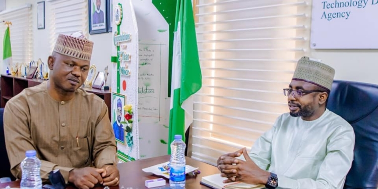 The Director-General, National Information Technology Development Agency (NITDA), Kashifu Inuwa and the Executive Secretary, National Commission for People with Disability (NCPWD), James Lalu sitting two feet from each other indoors. In between them is the Nigerian flag. On the wall is a picture of the president of Nigeria President Muhammadu Buhari.