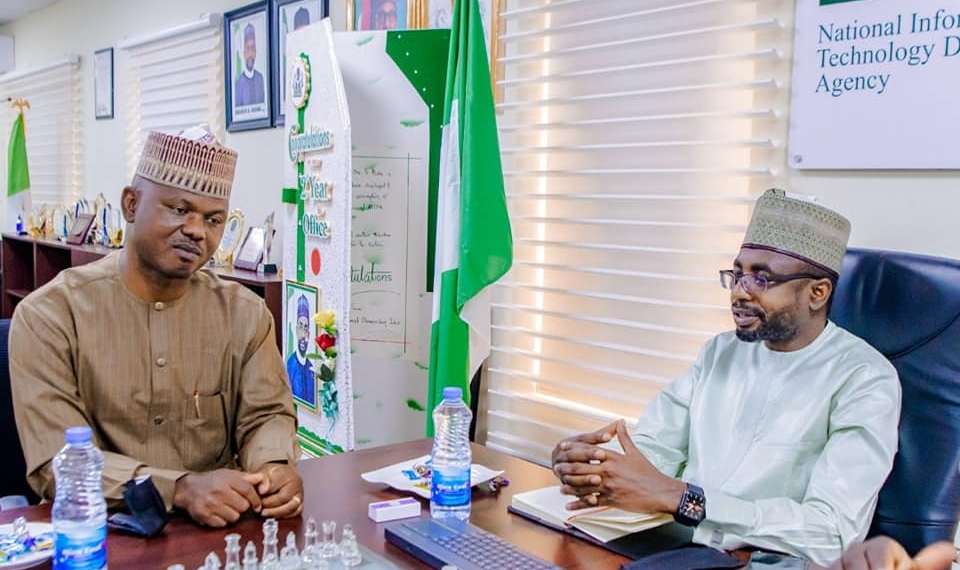 The Director-General, National Information Technology Development Agency (NITDA), Kashifu Inuwa and the Executive Secretary, National Commission for People with Disability (NCPWD), James Lalu sitting two feet from each other indoors. In between them is the Nigerian flag. On the wall is a picture of the president of Nigeria President Muhammadu Buhari.