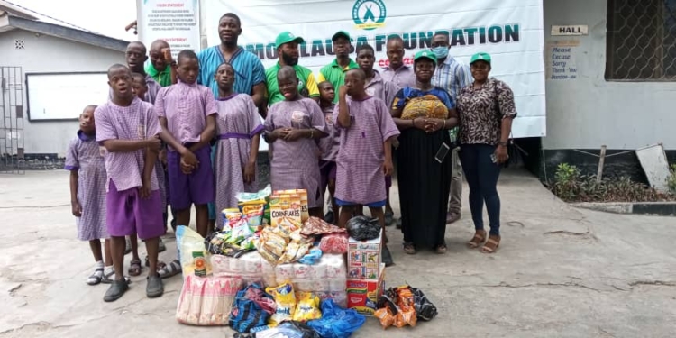 A group of people standing outdoor. There are food items on the floor in front of them