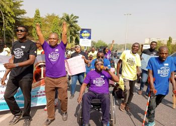 People outdoor on a road walking carrying placards