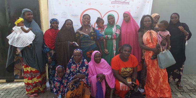 Women in a group picture with a banner at the background which reads Sesor Foundation