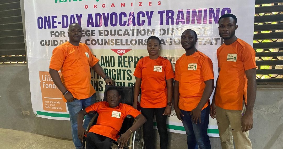 People in a group picture, one person is on a wheelchair and the dominant colour is orange