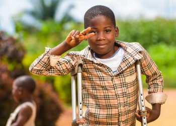 A young boy standing with support of clutches outdoor