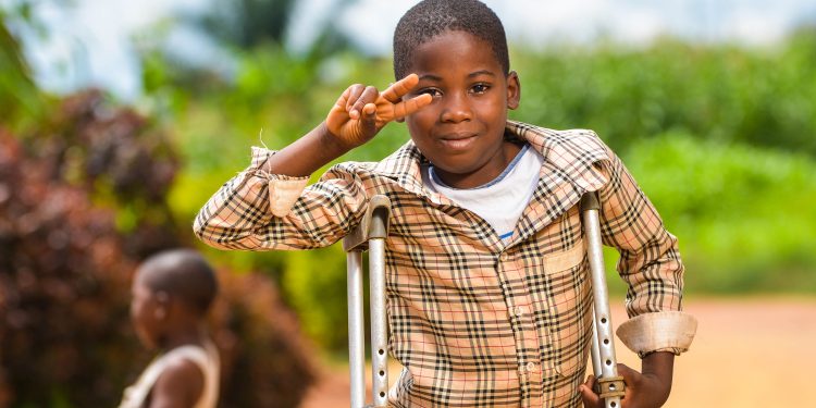 A young boy standing with support of clutches outdoor