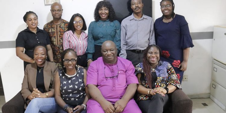 A group of people indoor. Four of them are sitting while five are standing.