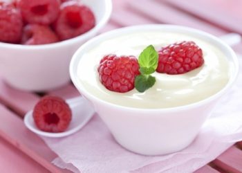 A white bow of yoghurt with strawberries in it.