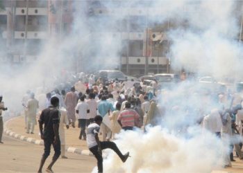 People out on the road running. There is white smoke from a canister on the road