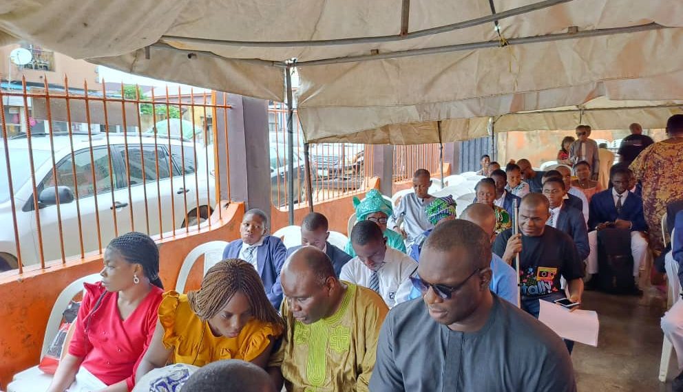 People seated under the canopy in the residence of the deceased